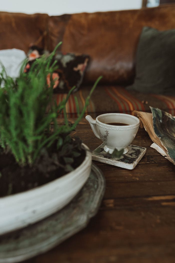 A rustic minimalist setup featuring a cup of coffee with greenery on a wooden table.