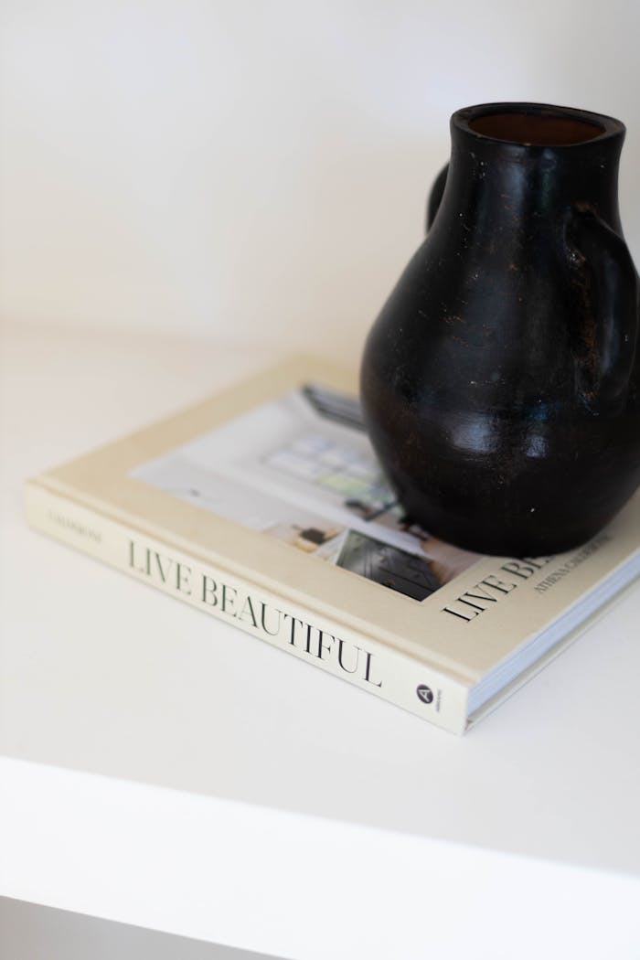 Simple black pottery on "Live Beautiful" book, embodying elegance.